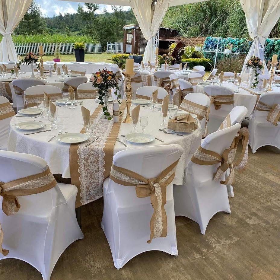 Réception de mariage sous chapiteau : tables rondes nappées de blanc, housses de chaise et nœuds en jute dentelle