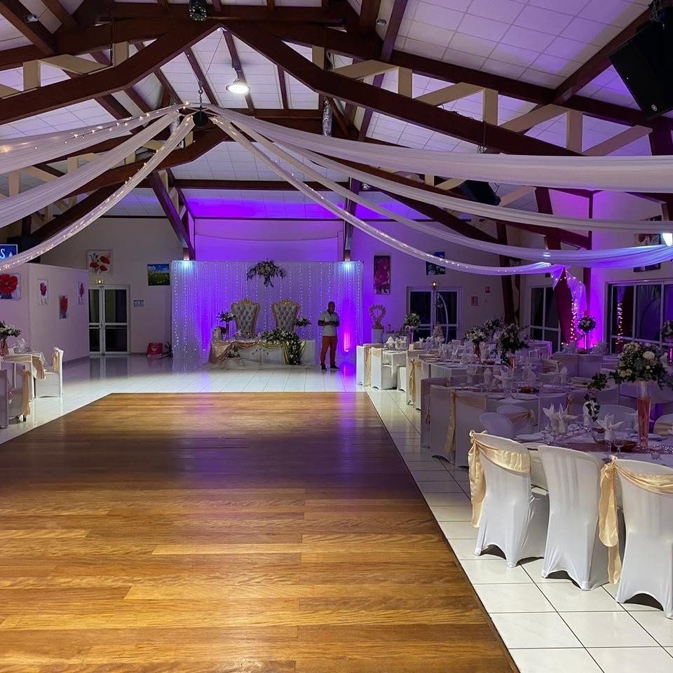 Salle décorée de tentures blanches au plafond, éclairage violet et chaises habillées